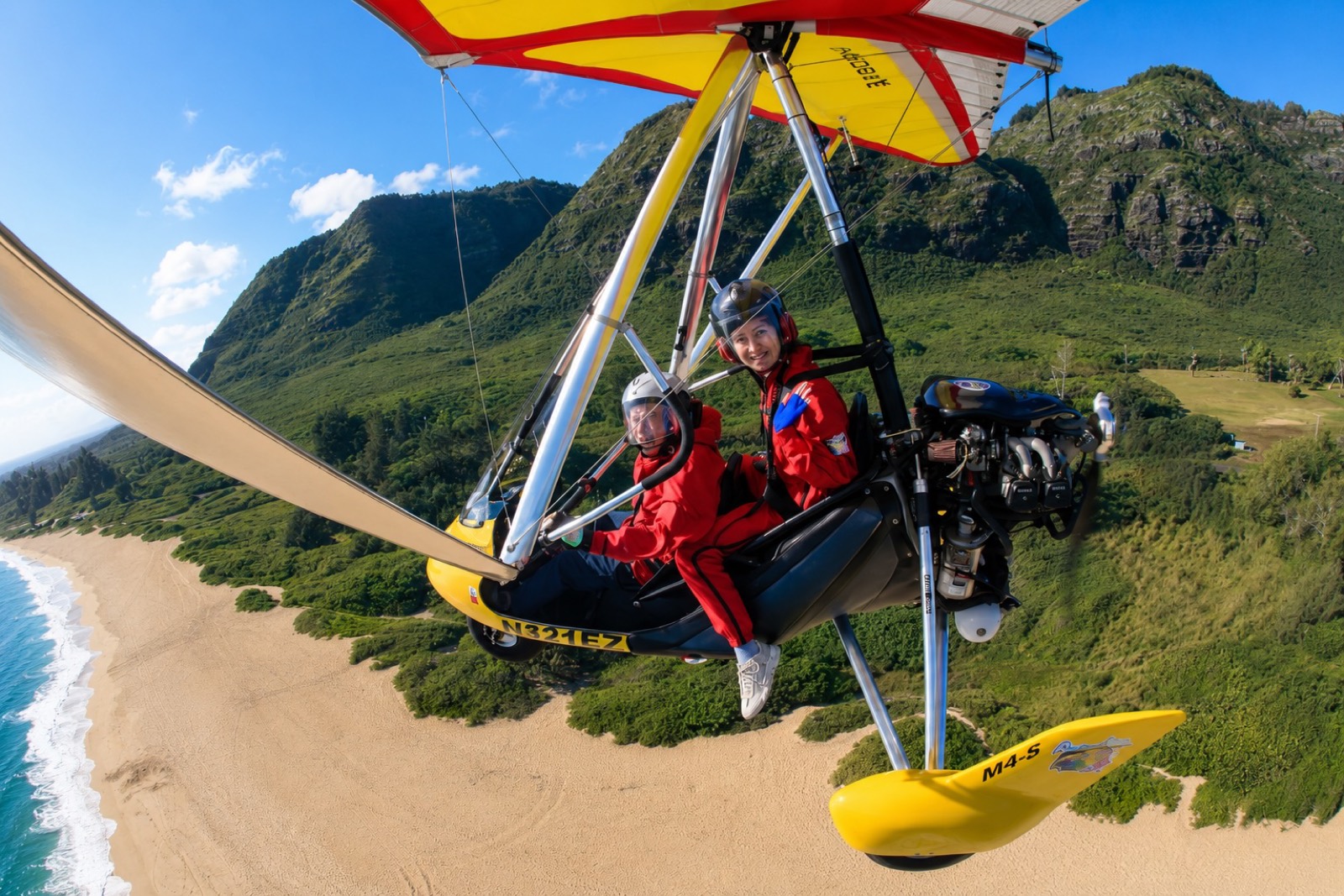 A first-time flyer and instructor in GoSky Hawaii's powered hang glider low over a North Shore beach